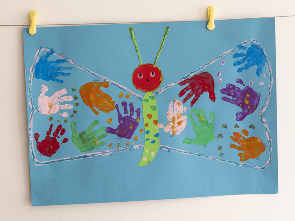 Bunte Handabdrücke der Kinder als Flügel eines Schmetterlings Bunte Handabdrücke der Kinder als Flügel eines Schmetterlings